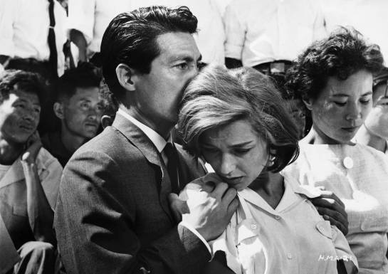 ca. 1959 --- Lui (Eiji Okada) holds Elle (Emmanuelle Riva) in a crowd. --- Image by © John Springer Collection/CORBIS